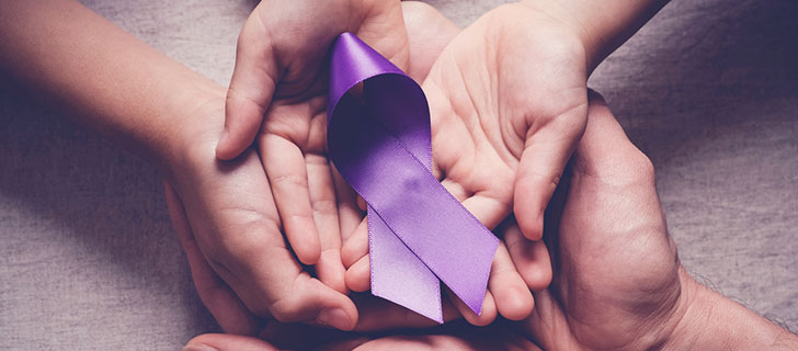 A purple awareness ribbon held in the cupped hands of an adult and a child.