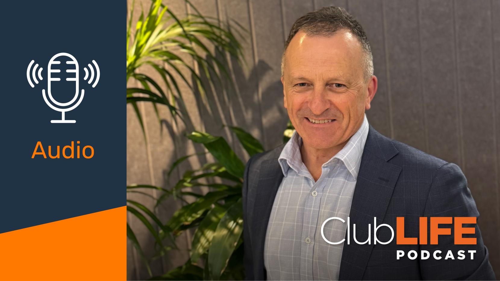 A smiling man in a suit jacket and checkered shirt. The image includes a 'ClubLIFE PODCAST' logo and an 'Audio' icon.